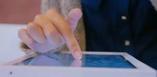 A hand pressing on a kiosk's touchscreen.
