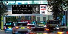 A long digital screen over a street. On display is an ad for Justin Bieber's album &quot;Purpose,&quot; and a note saying that it was playing at that moment on 95.8 Capital FM.