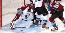 A goalie for a professional hockey team making a tough save against the opposition
