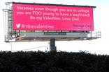 A pink billboard with the hashtag #mkevalentine. The text is from a Tweet that says "Veronica even though you are in college you are TOO young to have a boyfriend! Be my Valentine. Love Dad.
