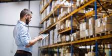 A man in a warehouse reviewing an order on his tablet