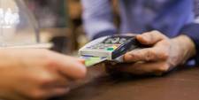 A close-up of a hand holding a bank card, about to pay for goods