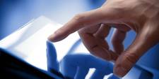A hand with an outstretched finger touching a touchscreen